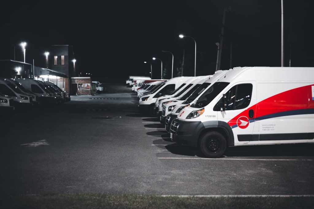 series of white vans parked on parking lot at night 12700835